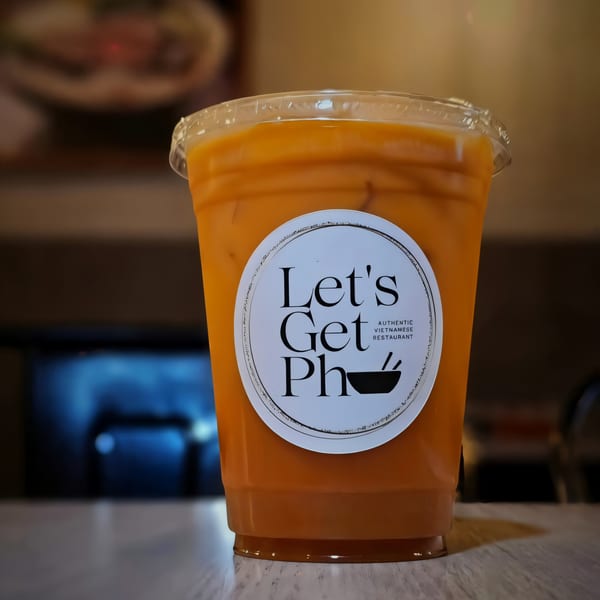 Iced Vietnamese coffee in a clear plastic cup with the "Let's Get Pho" logo.
